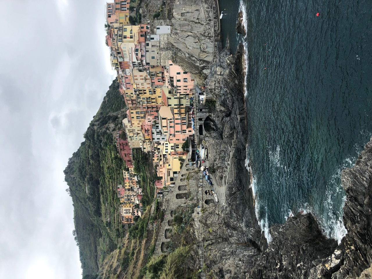 Colorful hillside homes above a rocky harbor in Cinque Terre