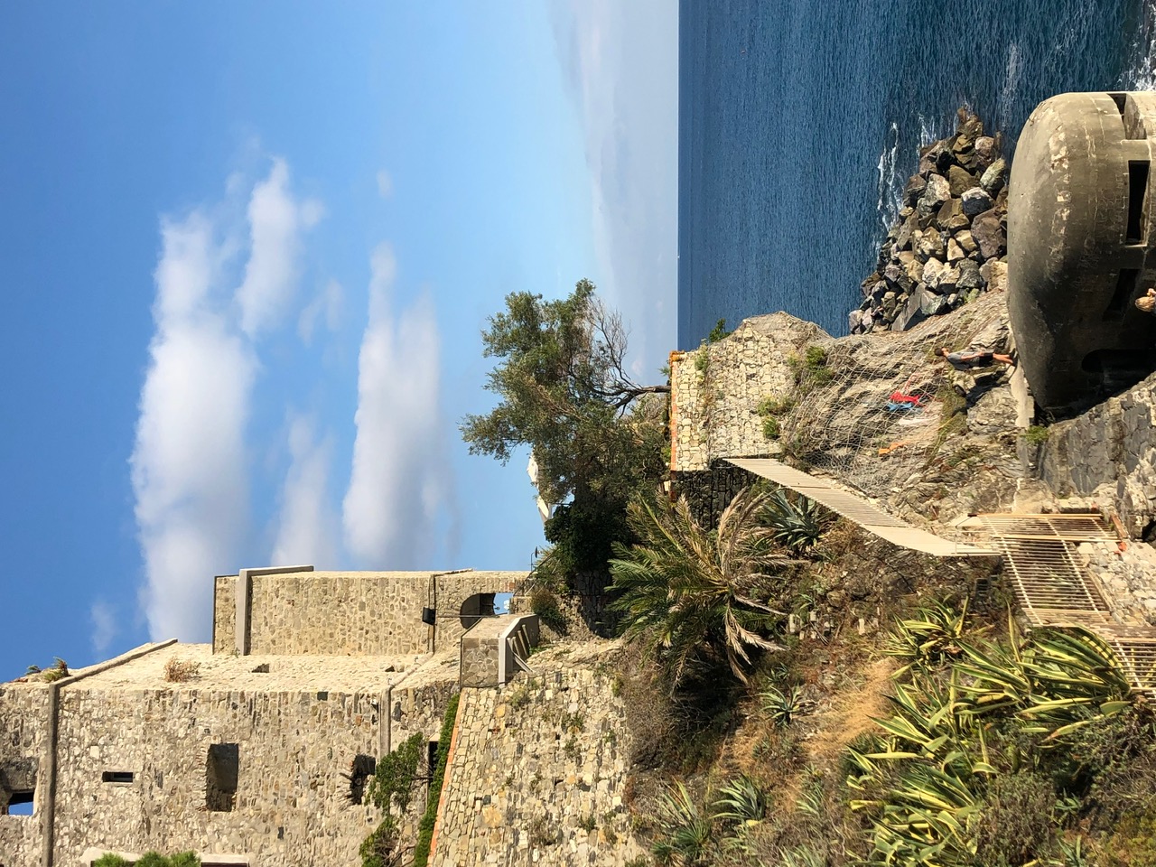 Stone buildings and cliffside stairs above the Italian coastline